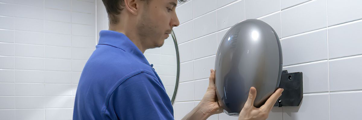 Image showing an Initial technician servicing an Initial Hand dryer in a washroom.